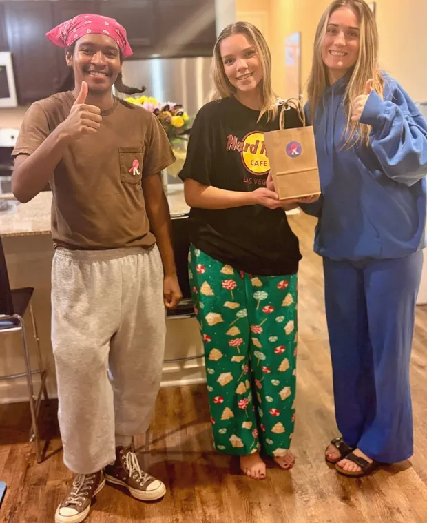 A Kempt cleaner in the company's pink bandana with customers holding a Kempt gift bag after a clean