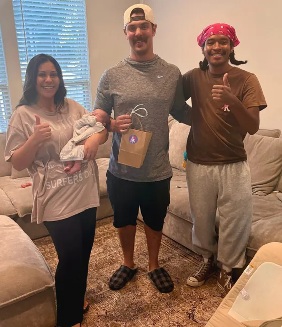A Kempt cleaner in the company's pink bandana with a family, all smiles, holding a Kempt gift bag
